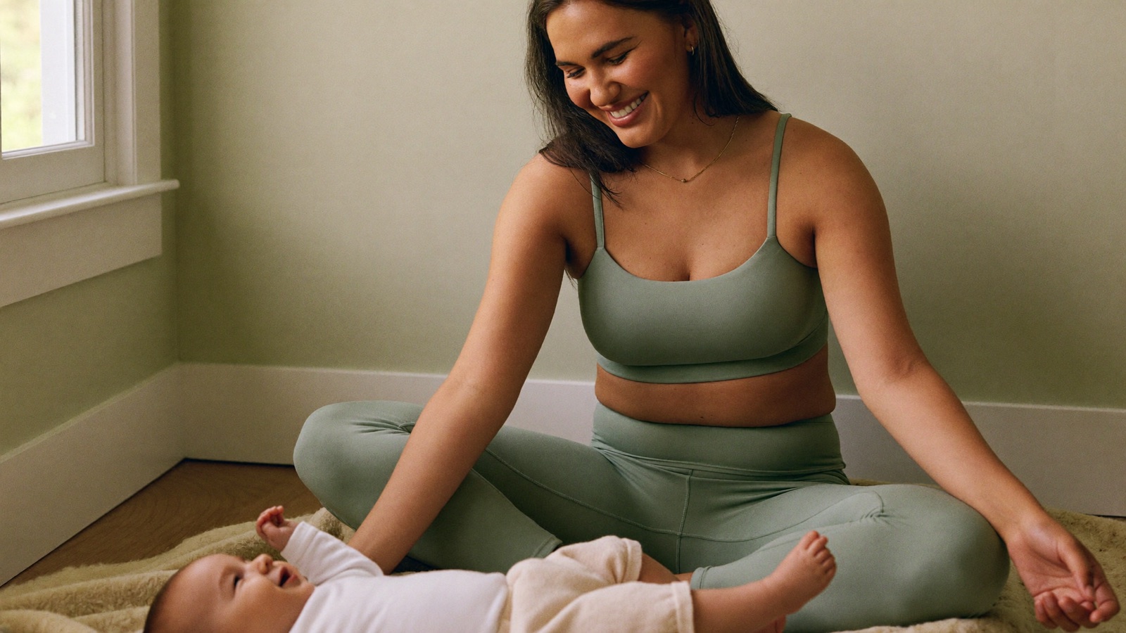 A smiling mum sitting with her baby, ready for early access to Hello Mumma